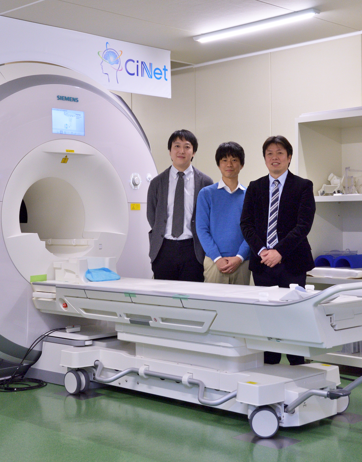 CiNetのfMRIと、「NeuroAI® D-Planner」の開発チーム。左から、茨木拓也（NTTデータ経営研究所）、西本伸志博士、矢野亮（NTTデータ） （写真提供：情報通信研究機構 脳情報通信融合研究センター ©Takashi Matsui / DIAMOND Online）